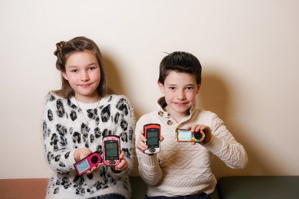 A boy and a girl are holding cell phones in their hands.
