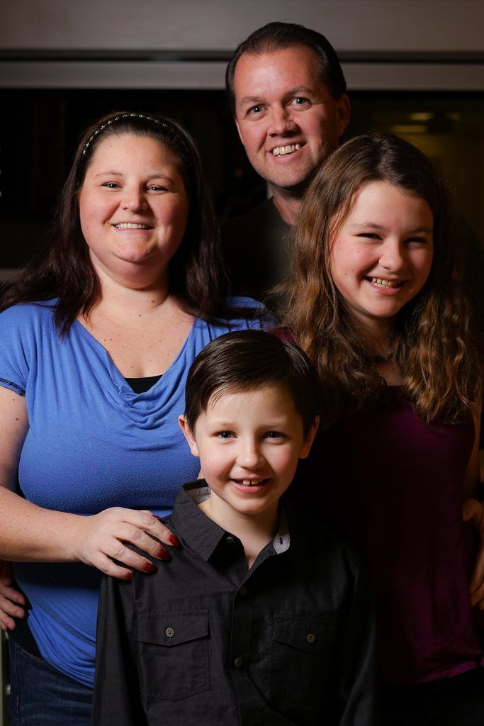 A family is posing for a picture together and smiling for the camera.