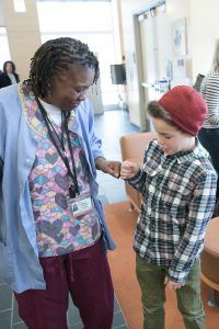 A nurse is holding the hand of a young boy in a hospital.