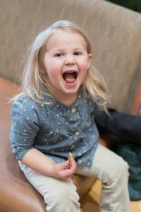 A little girl is sitting on a couch with her mouth open.