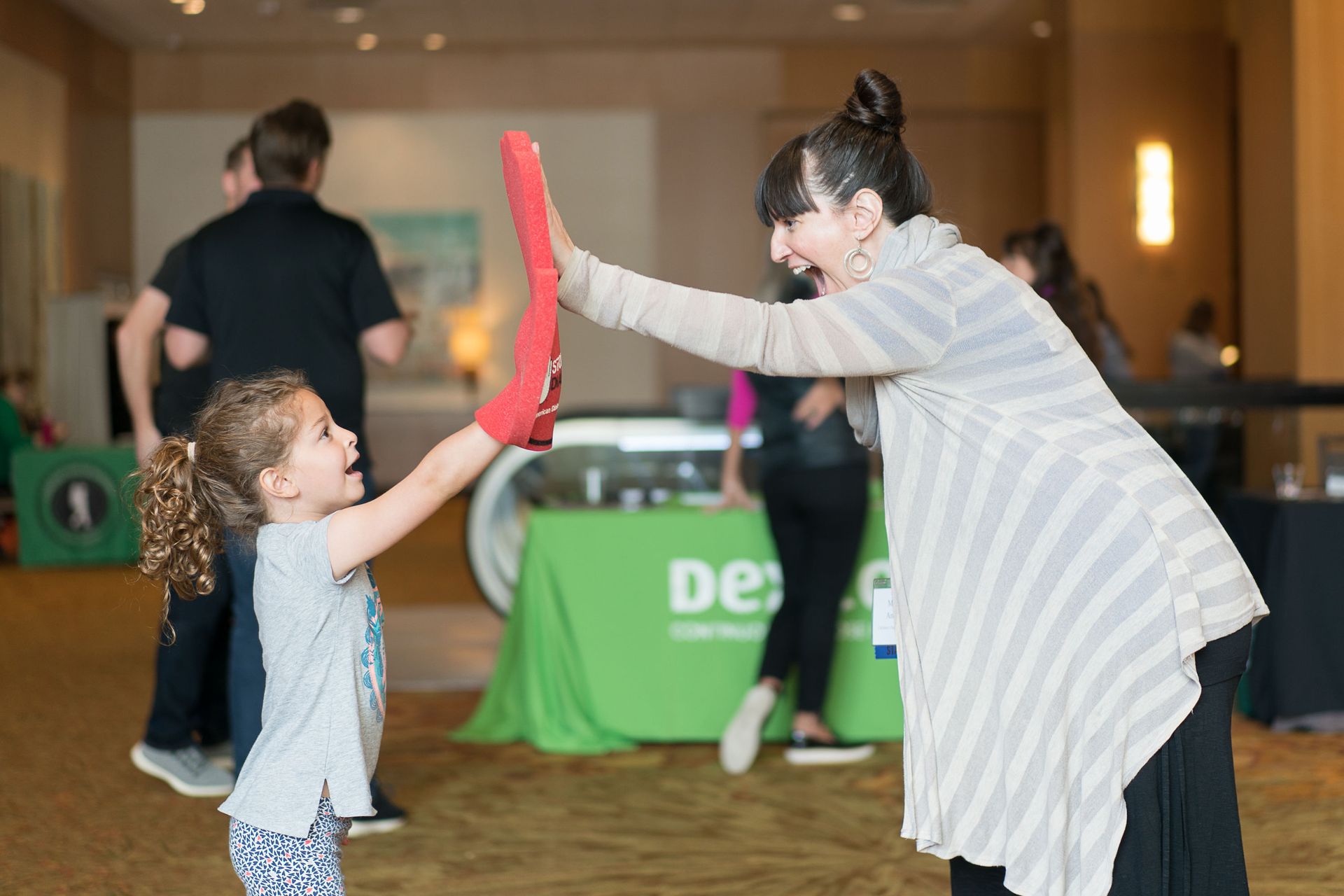 Young girl with foam finger giving high five to female staffer at EPIC conference.