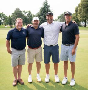 Four men are posing for a picture on a golf course