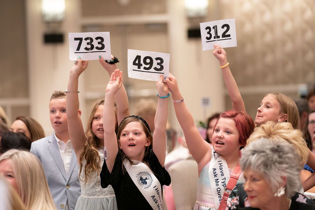Several young T1D Advocates holding up bidding numbers during live auction at BRL.