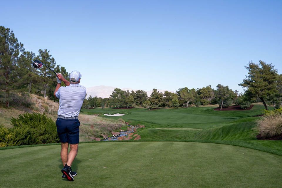 Male golfer in his backswing on the tee box, watching where his ball went.