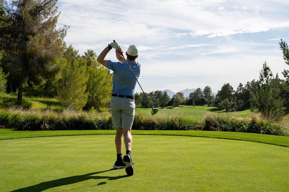 A man is swinging a golf club on a golf course.