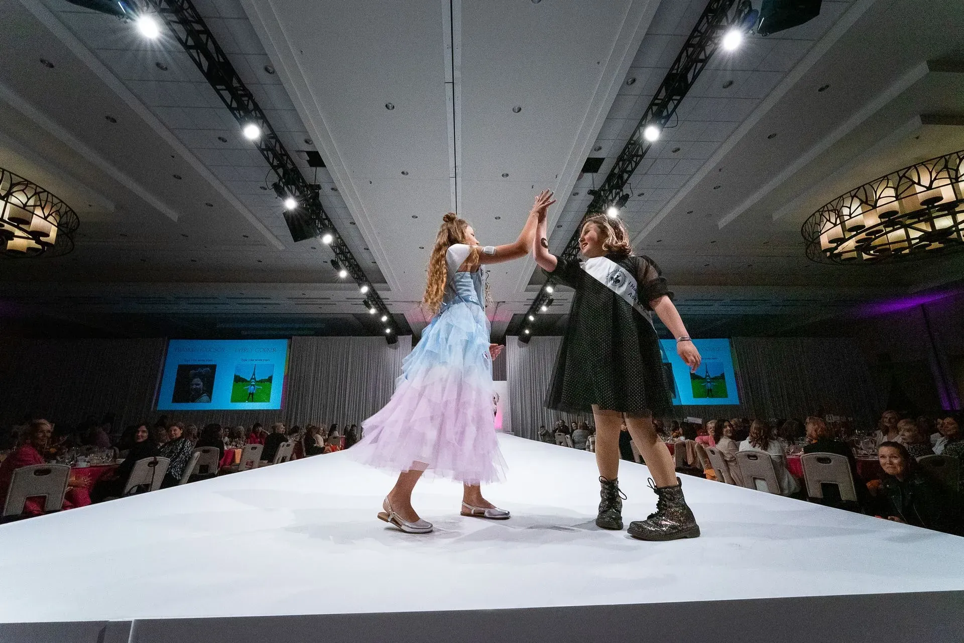 Two kids high fiving at the Brass Ring Luncheon and Fashion Show. 