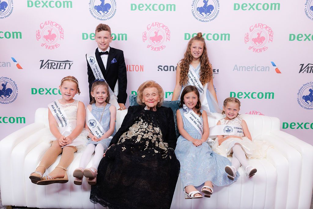 Barbara Davis seating on couch with several young CDF advocates at The Carousel of Hope.