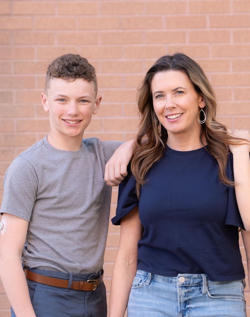 Mother and teenage son standing together and smiling.