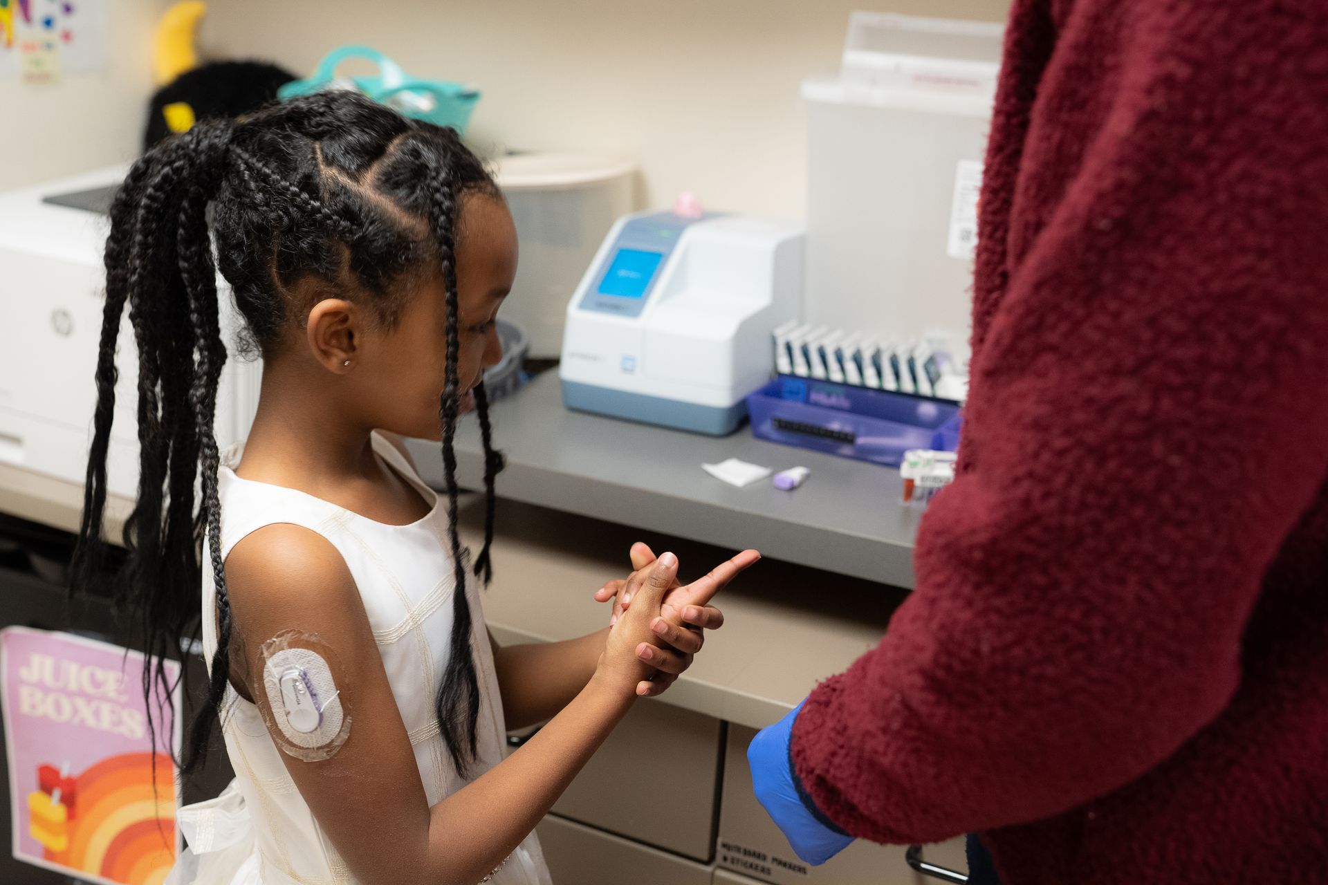 Young girl with CGM getting her blood drawn from fingertip by medical staff at the BDC.