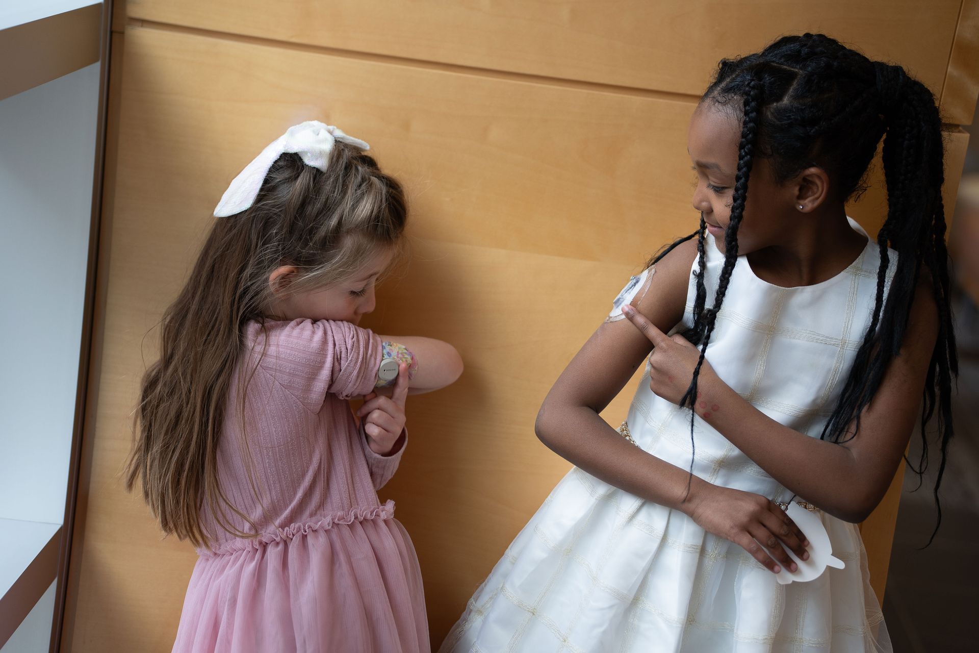 Two young girls showing each other their CGM devices the back of on their arms.