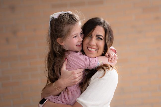 Young girl with CGM hugging and smiling with her mom.