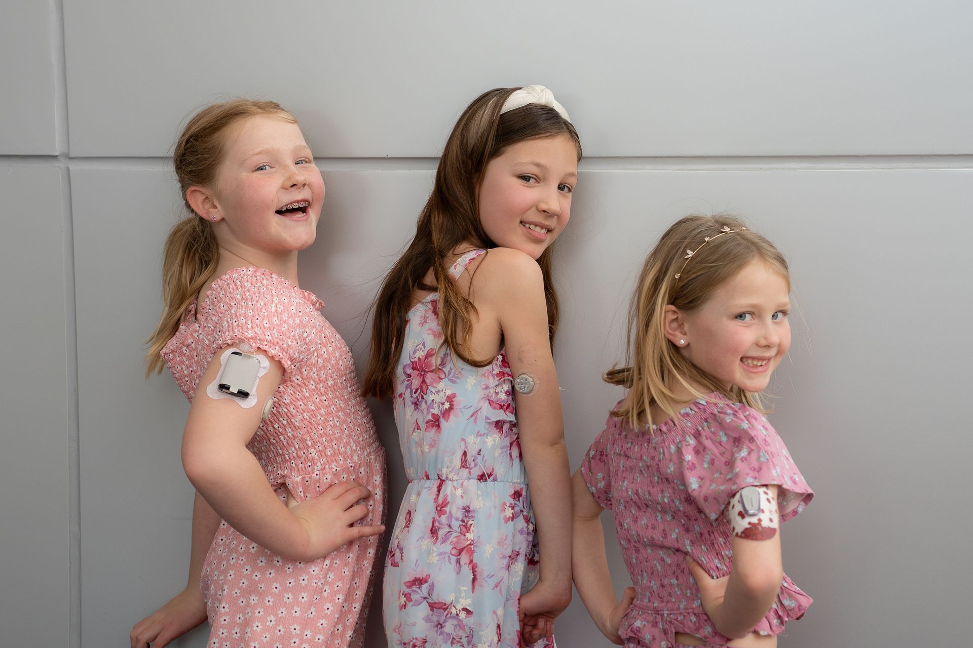 Young blonde girl with insulin pump on her arm in a pink shirt. 