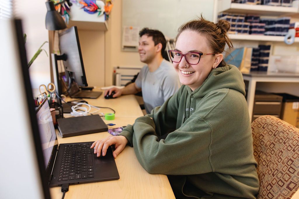 Female and male teenagers sitting at a desk on their laptops.