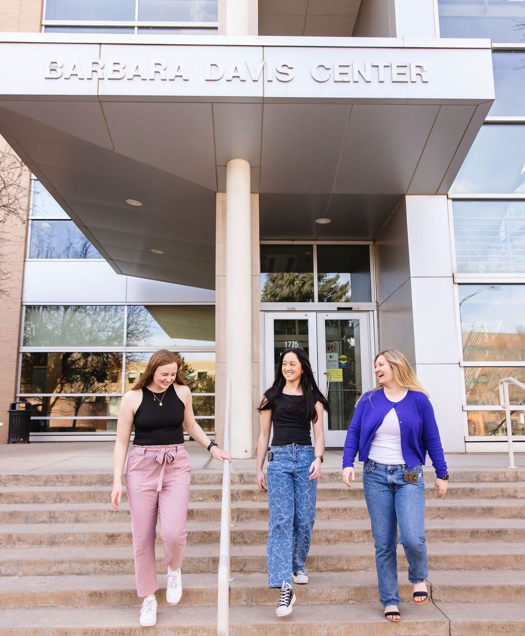 Three smiling women walking out of the Barbara Davis Center.