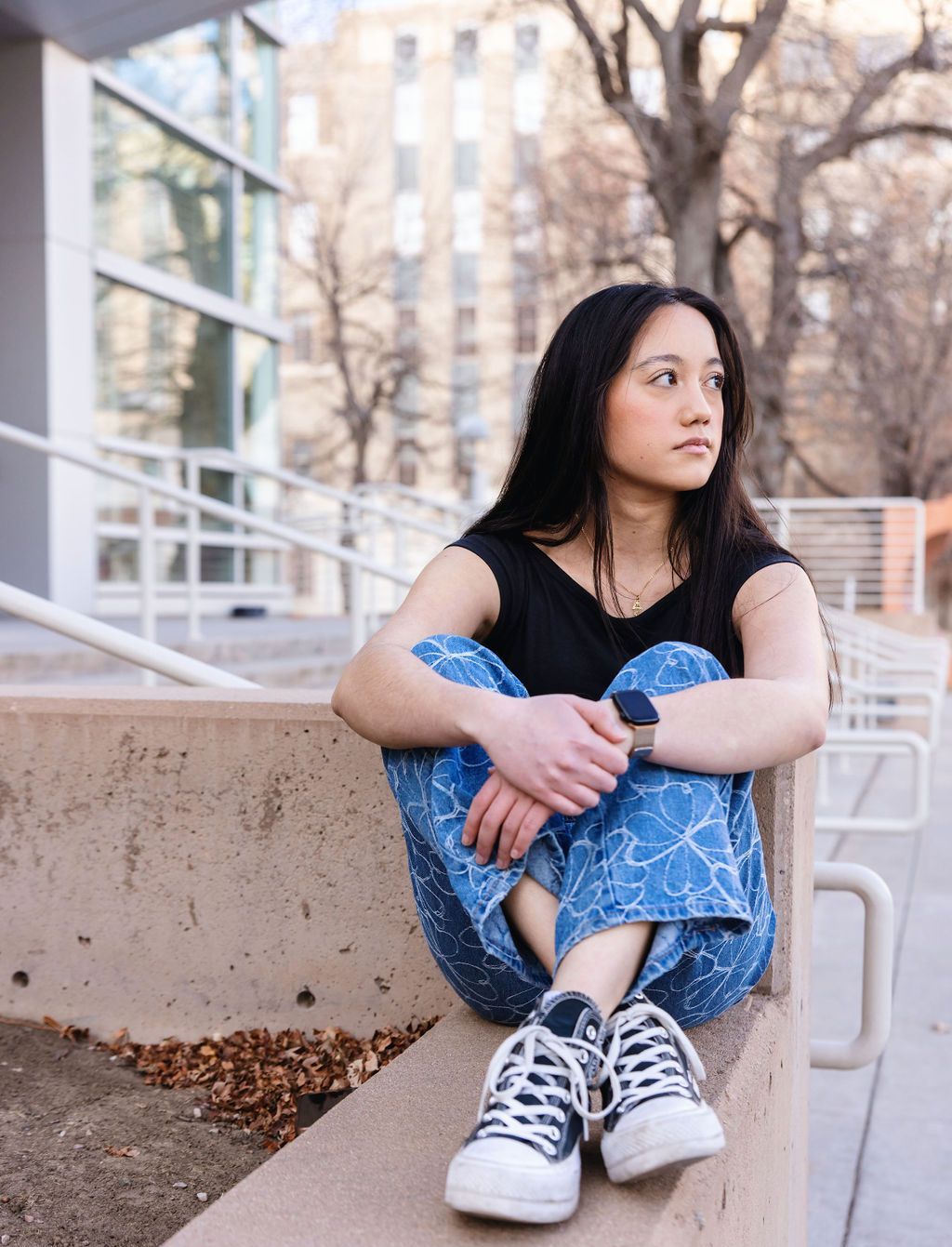 Young woman sitting on steps and looking contemplative.