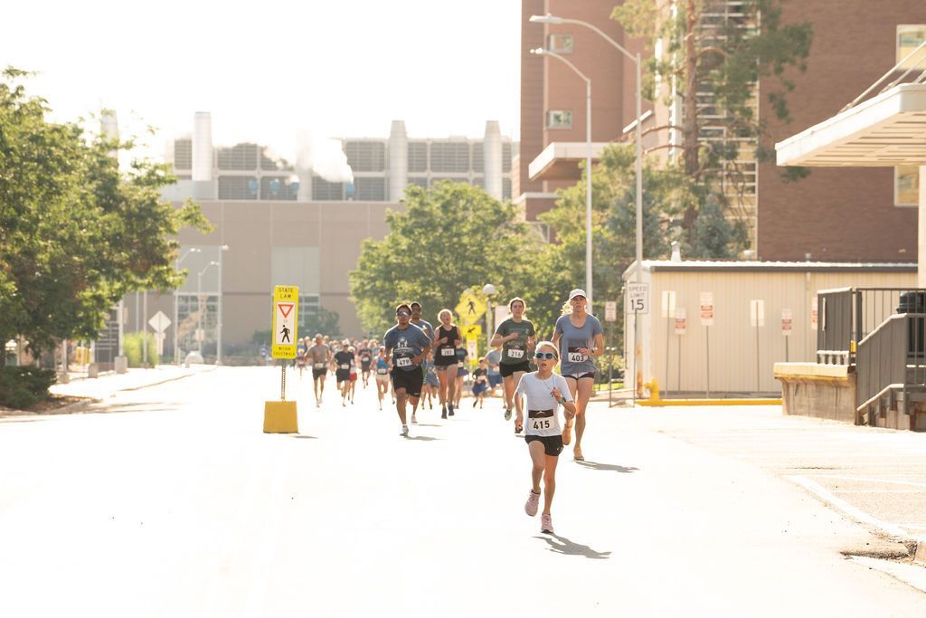 group of 5k runners on race course led by young girl in sunglasses