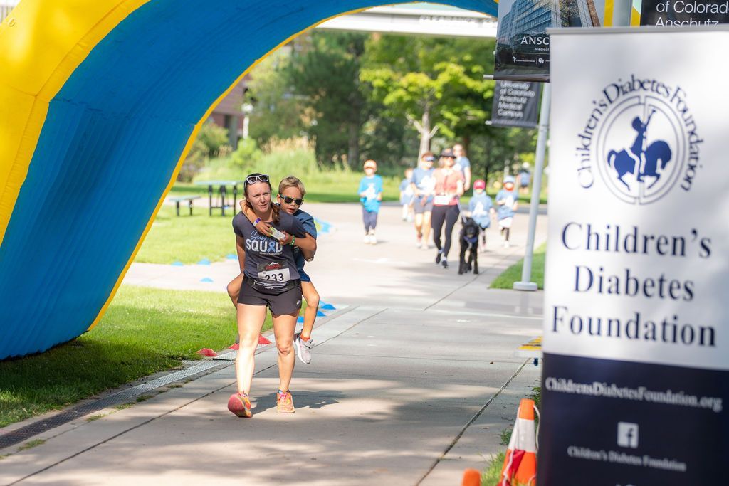 mom carrying son piggy back during race and both are laughing