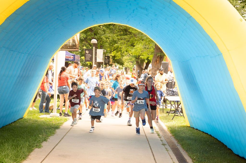 young runners racing underneath inflatable arch