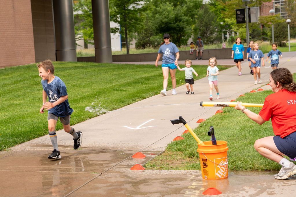 boy getting sprayed by water gun and laughing during race