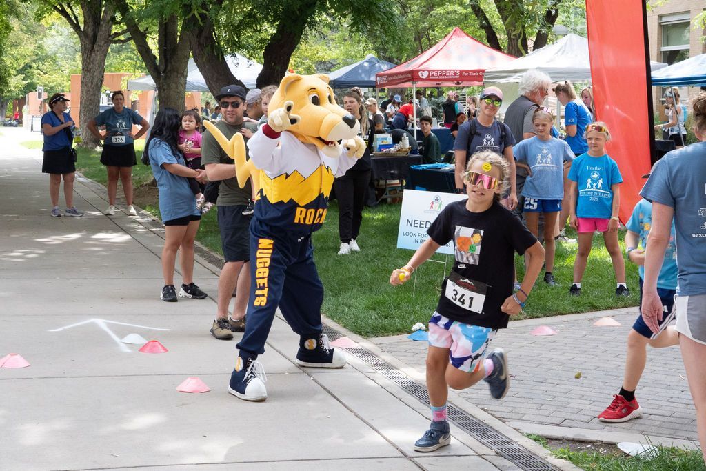 Denver Nuggets mascot Rocky cheering on young runner during kids race