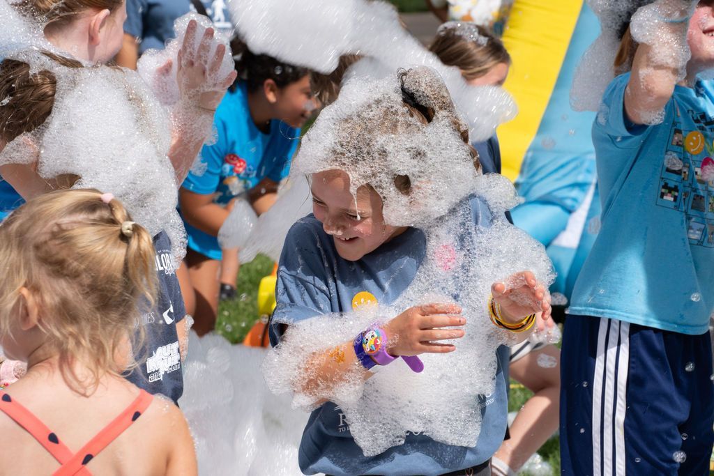 girl covered in foam at outdoor foam party and laughing