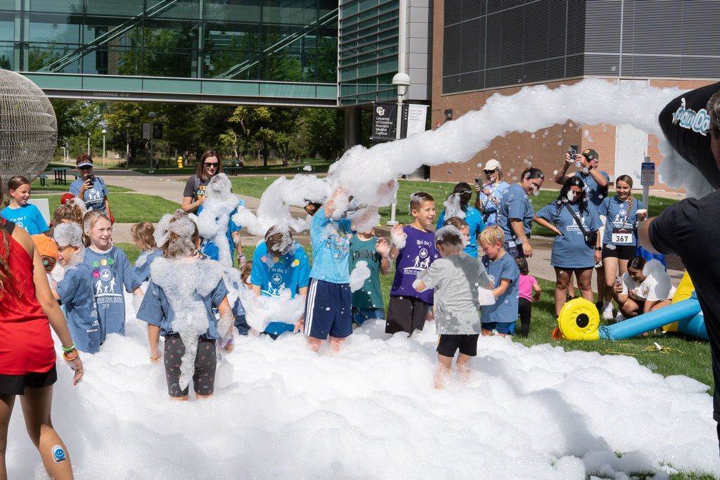group of children laughing and playing in an outdoor foam party