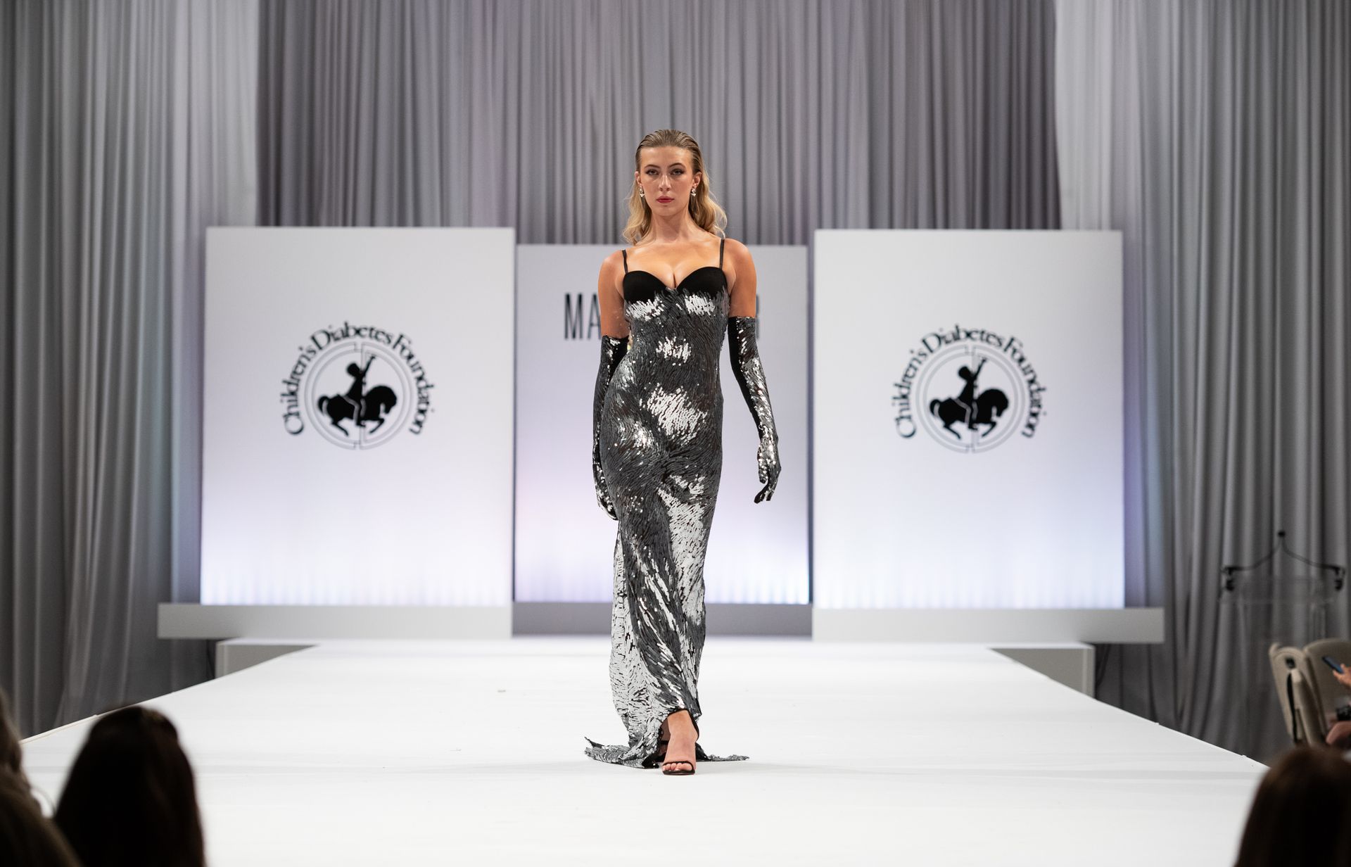 Model walks the runway in a silver dress at the Brass Ring Luncheon and Fashion Show. 