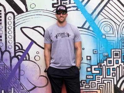 A man is standing in front of a wall with graffiti on it.
