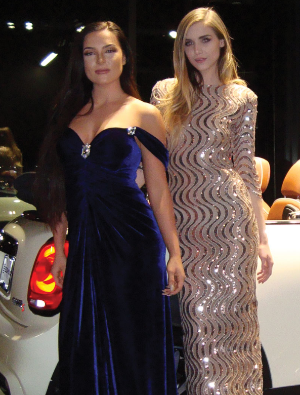 Two women standing next to each other in front of a white car