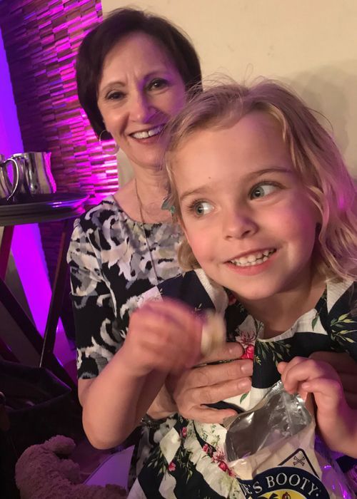 A woman and a little girl are sitting next to each other and smiling.