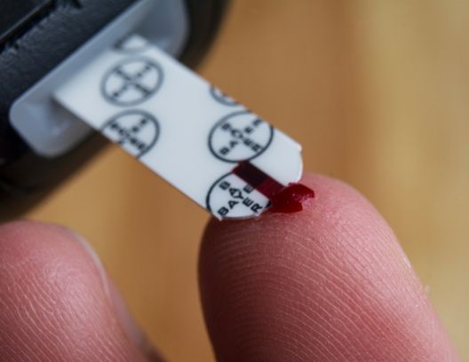 Closeup image of someone pricking their finger to test blood