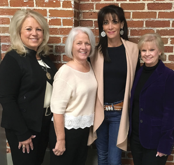 Four women posing for a picture in front of a brick wall