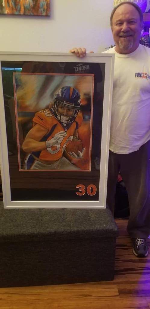 A man is holding a framed picture of a football player.
