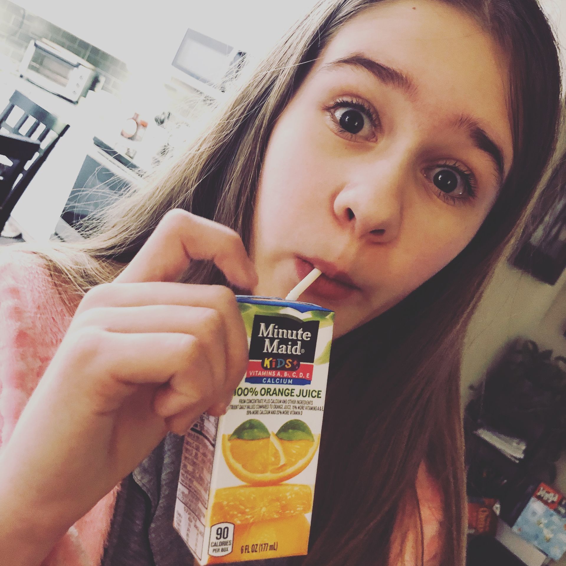 A girl drinking orange juice from a minute maid box