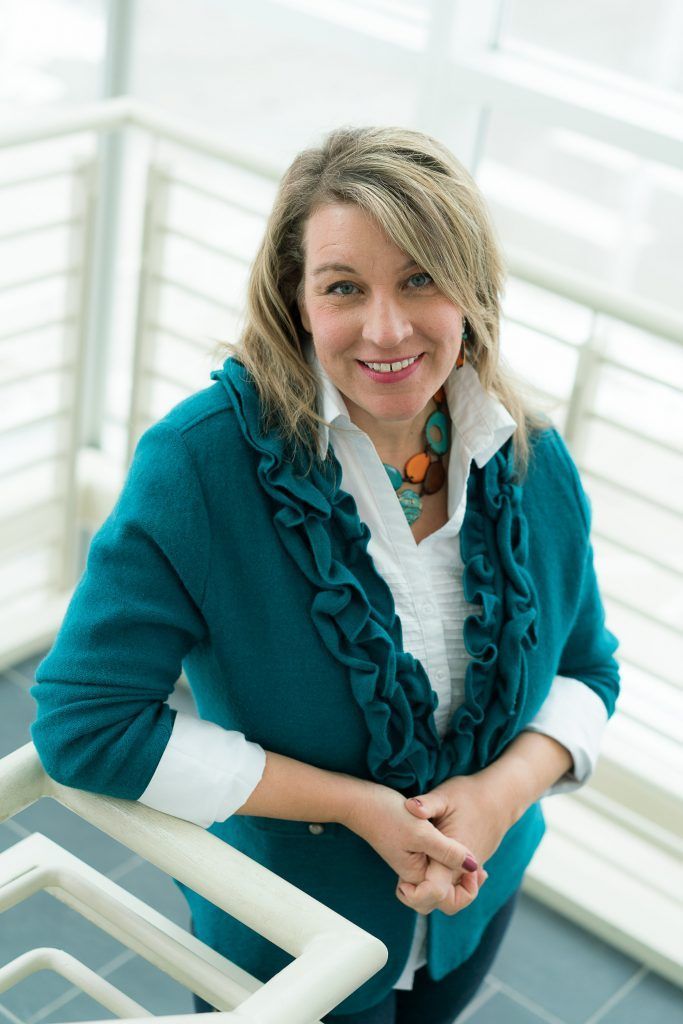 A woman in a blue sweater is standing next to a railing
