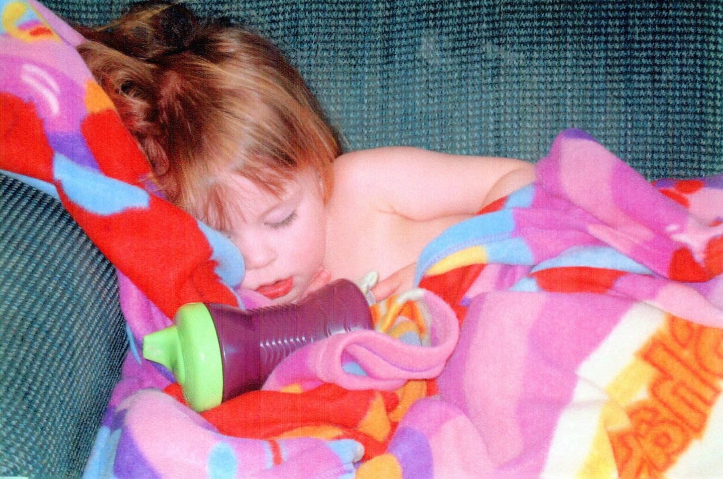 Natalie as a toddler sleeping on the couch under a blanket
