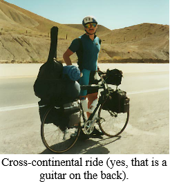 A man riding a bike with a guitar on the back