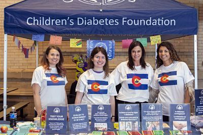A group of women are standing in front of a children 's diabetes foundation tent.