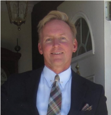 A man in a suit and tie is smiling for the camera