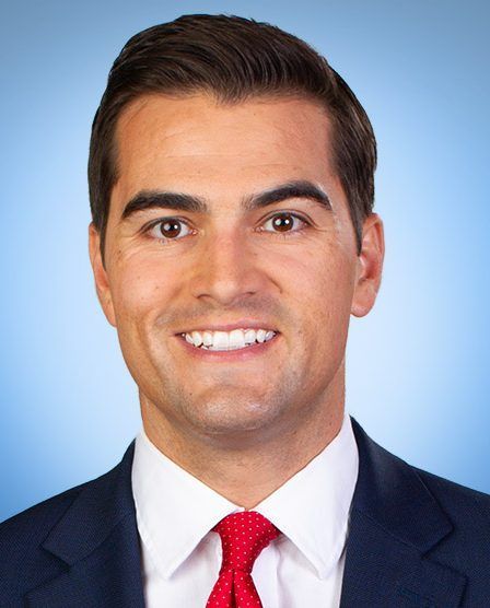 A man in a suit and tie is smiling for the camera