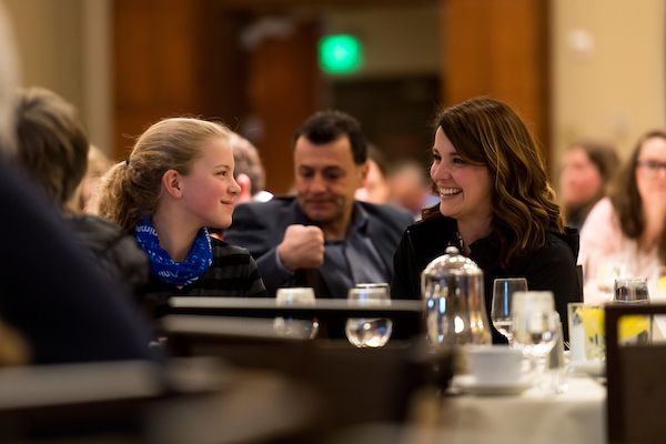 A group of people are sitting at a table talking to each other.