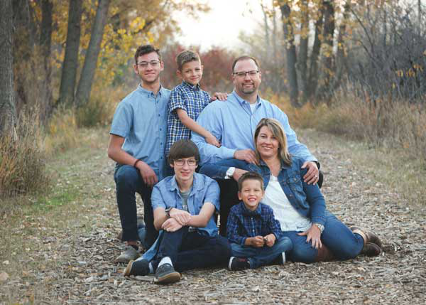 A family is posing for a picture while sitting on the ground in the woods.