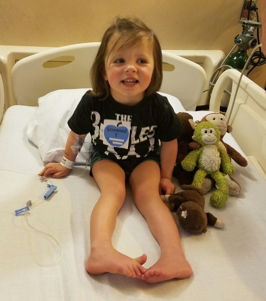 A little girl wearing a shirt that says the beatles is sitting in a hospital bed