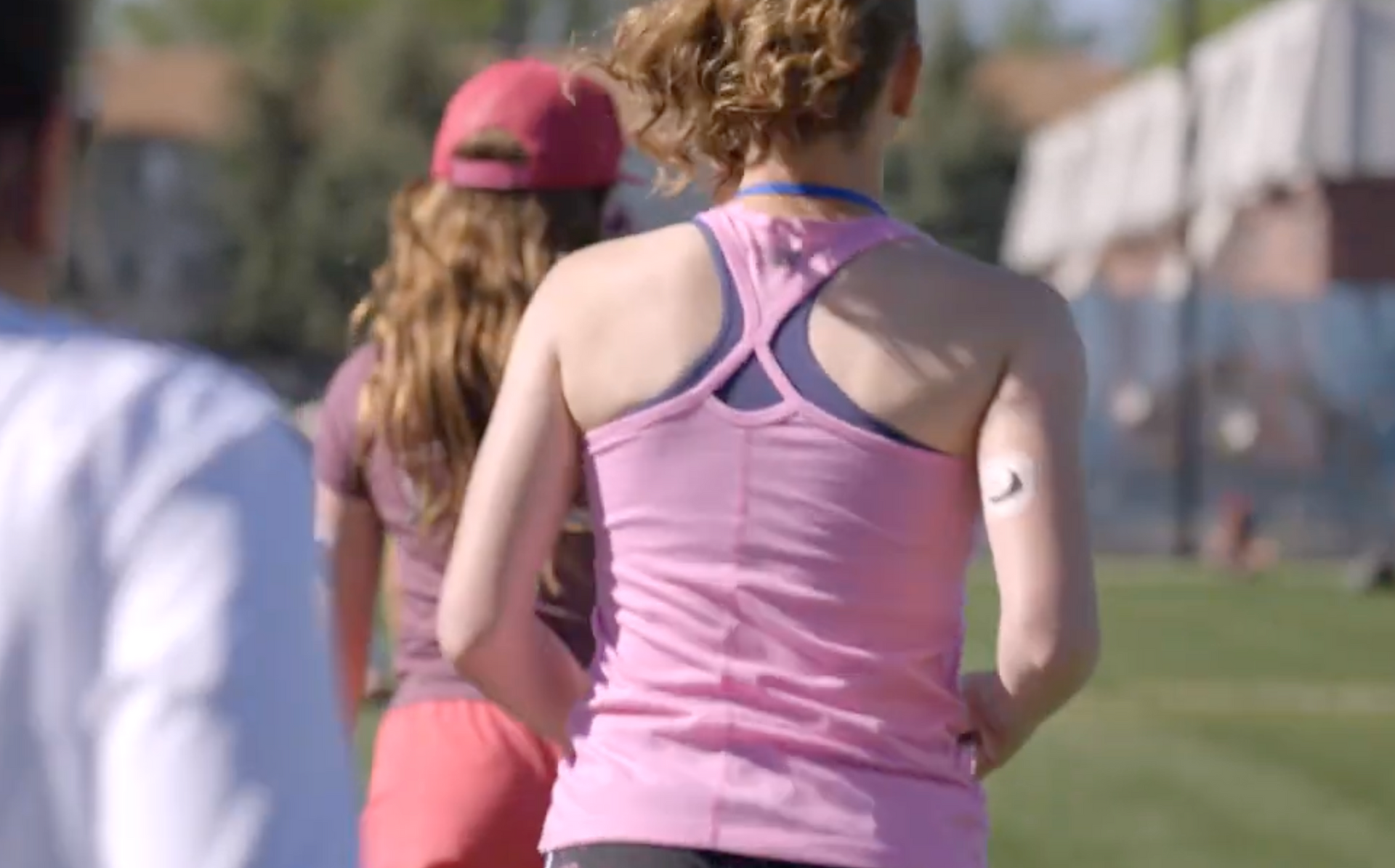 Teen girl with CGM on back of arm running with others.