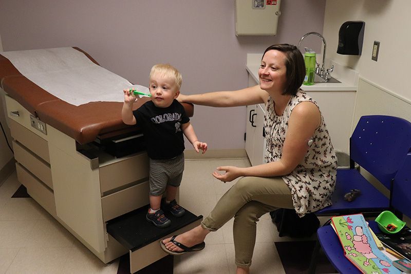 A woman is sitting next to a little boy in a doctor 's office.