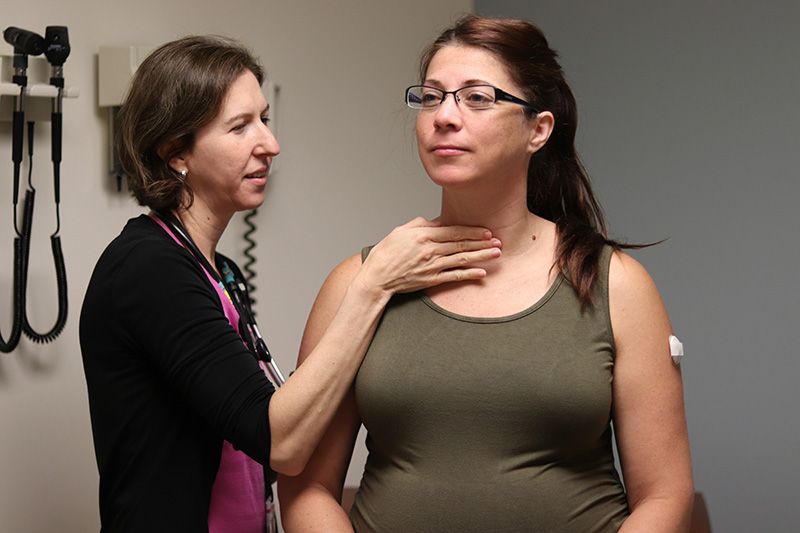 Dr. Polsky, head of the pregnancy clinic, examining a young mother-to-be in exam room.