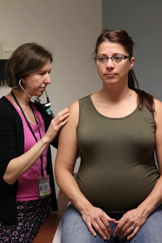 A pregnant woman is being examined by a doctor with a stethoscope