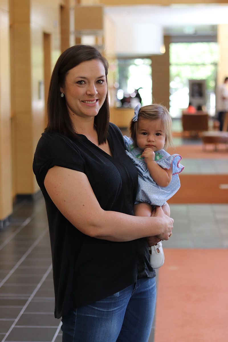 A woman is holding a baby in her arms in a hallway.