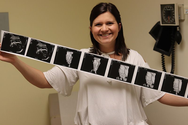 A woman in a white shirt is holding a row of black and white photos