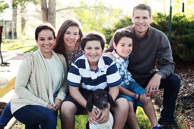 A family is posing for a picture with a dog.